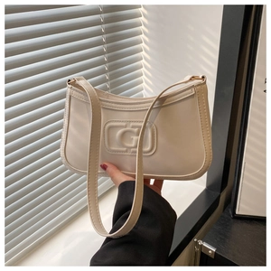 Detail of cream white underarm bag featuring embossed G logo and gold metal hardware