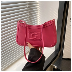 Detailed close-up of hot pink shoulder bag featuring an embossed G logo on faux leather