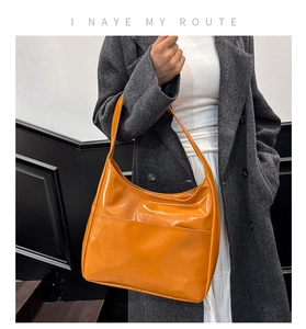 Close-up of orange vintage faux leather hobo bag featuring FASHION text detail