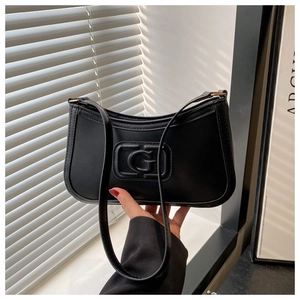 Detail of black matte faux leather baguette bag with G logo and golden metal hardware