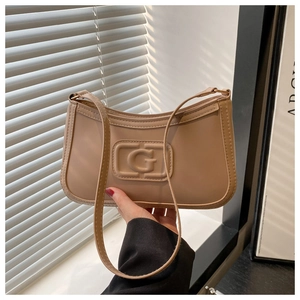 Close-up detail of beige leather bag with embossed G logo and fine vertical stitching