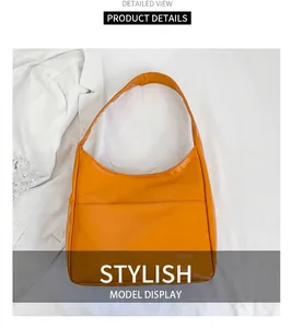 Close-up of bright orange faux leather shoulder bag with white Fashion text detail