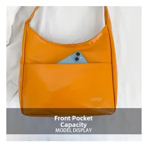 Detail of the front pocket on the orange faux leather tote bag showing storage capacity