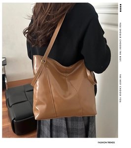 Détail du sac cabas en cuir verni marron avec surpiqûres croisées porté à l'épaule