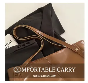 Detail of caramel faux leather tote bag with silver studs on brown suit jacket