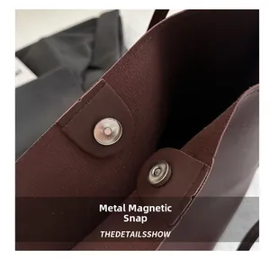 Close-up of the vintage burgundy tote bag featuring a secure magnetic metal snap closure