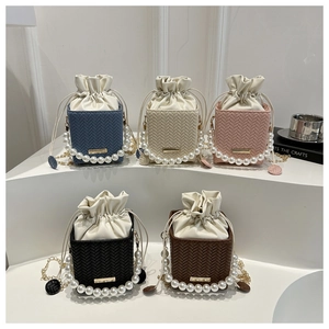 Detail view of woven leather bucket bags in five colors with pearl handles and chain straps