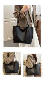 Detail of a large black minimalist tote bag showing structured matte texture and shoulder straps