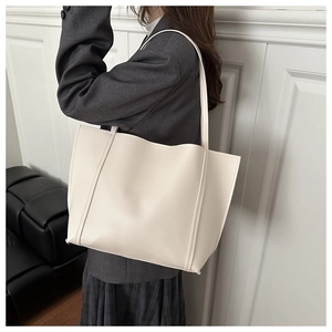 Detail of minimalist cream tote bag showing smooth leather texture and stitching