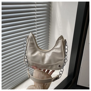 Detail of cream half-moon bag with silver metal chain and fashion embossed text