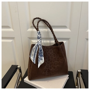 Detail of dark brown leopard texture tote bag with woven handles and silk scarf detail