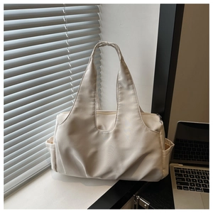 Detailed side view of beige large-capacity tote bag showing smooth fabric and side pockets