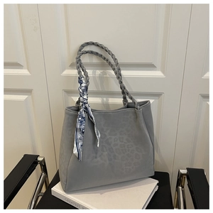Detail of grey leopard tote bag featuring woven handles and a blue patterned silk scarf