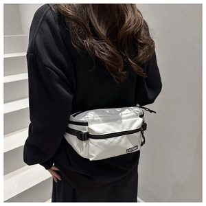 Close-up of white nylon fanny pack with black zippers and adjustable sport strap