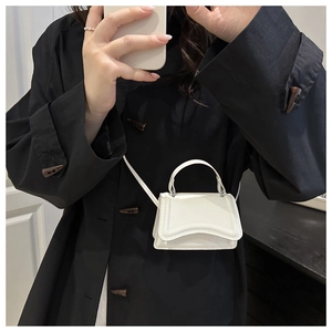 Close-up of off-white mini crossbody bag with top handle and fine stitching detail