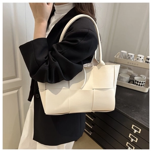 Detailed side view of beige large woven leather tote bag with thick strap handle