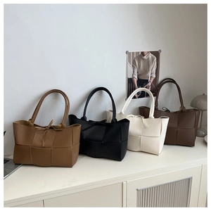 Detailed view of woven leather tote bags in brown, black, white, and coffee colors