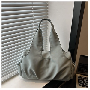 Detail of light green pleated canvas tote bag with side pockets by a window