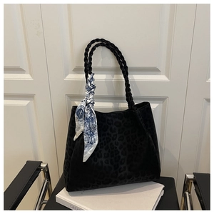 Detail of black leopard print tote bag with woven handles and a decorative silk scarf
