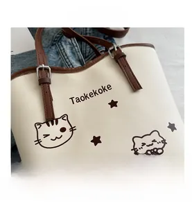 Close-up of cream tote bag with brown adjustable strap and cute cartoon cat pattern