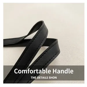 Detail view of the black textured leather handle with durable double stitching on the tote