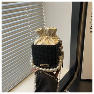Detail of woven black bucket bag with pearl handle and cream drawstring lining
