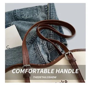 Detail of dark brown leather handle with silver metal buckle on a beige tote bag