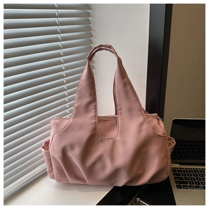 Detail of pink nylon tote bag showing the side pocket and thick handles on a desk
