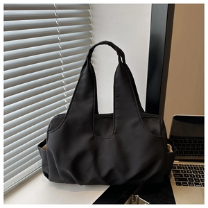 Detail of black pleated canvas tote bag showing spacious capacity and side pocket texture