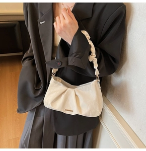 Dettaglio dell'elegante manico a pieghe della borsa a tracolla crema in pelle PU
