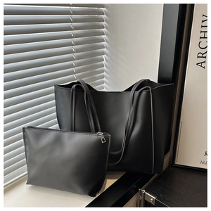 Detail of minimalist black matte leather tote bag set including inner zipper pouch and straps