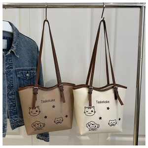 Detail view of khaki and cream tote bags with cartoon cat print and brown straps