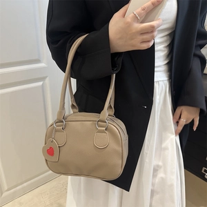 Borsa Boston in pelle marrone con ciondolo a cuore indossata da modella stile minimal