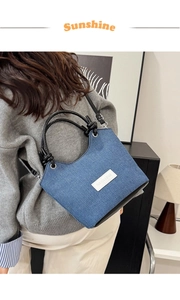 Détail du sac seau en denim avec bandoulière en cuir et étiquette mode sur l'épaule
