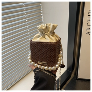 Detail of coffee woven bucket bag with cream drawstring pouch and pearl top handle