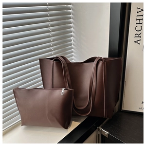 Detail of dark brown faux leather tote bag set with matching zipper pouch in natural light