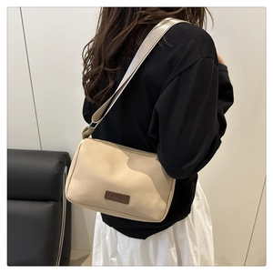 Détail d'un sac à bandoulière en toile beige avec étiquette en cuir et sangle textile