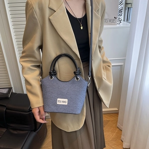 Sac seau bleu-gris avec anses rondes noires et bandoulière porté par un mannequin