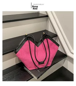 Detail of rose red corduroy tote bag featuring black leather trim and brand label