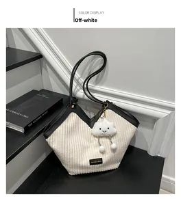 Detail of off-white corduroy tote bag with V-shaped opening and smiley cloud charm