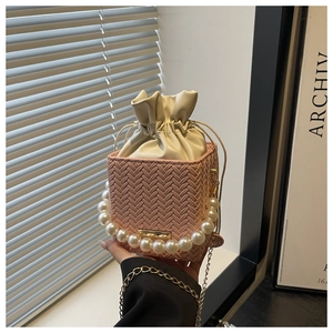 Pink woven square bucket bag with pearl handle, chain strap and drawstring lining detail