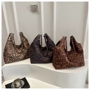 Detail view of three leopard print tote bags in tan, purple, and coffee on a white pedestal