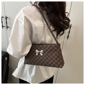 Detail of a brown leather shoulder bag with M pattern and silver butterfly buckle clasp