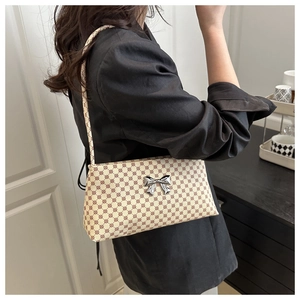 Close-up of retro printed shoulder bag with metallic silver bow decoration on woman