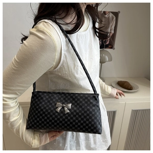 Detail of a chic shoulder bag with silver bow accent and geometric texture finish