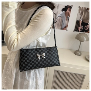 Detail of grey shoulder bag with M-pattern jacquard and silver butterfly bow ornament