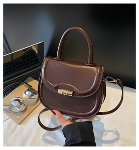 Close-up of chocolate brown PU leather bag with gold rotating lock and top handle