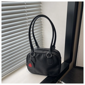 Detail of black lychee grain bowling bag featuring a red heart charm on the handle