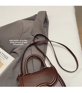 Detail view of adjustable shoulder strap and gold hardware on dark brown saddle bag