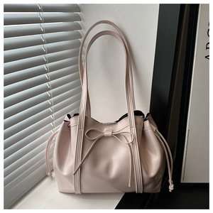 Detail of light pink patent PU leather tote bag with bow accent and side drawstring